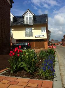 ein Haus mit einem Blumenbett davor in der Unterkunft Hotel Die Friesenhalle in Bredstedt