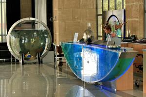 a woman standing in front of a desk with a blue object at All Senses Ocean Blue Sea Side Resort - All Inclusive in Kremasti