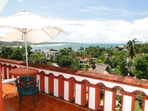 a balcony with a table and an umbrella and the ocean at Hotel Paraiso Escondido in Puerto Escondido