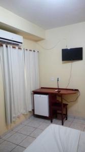 a room with a desk and a television on the wall at Hotel Fênix in Barreiras
