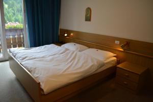 a bedroom with a bed with white sheets and a window at Hotel Val Di Fassa in Soraga