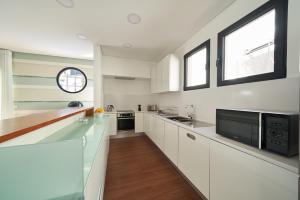 a white kitchen with white cabinets and a window at Funchal Charming Villa in Funchal