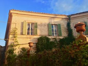 un edificio con finestre con persiane verdi e un idrante di La Corte Di Alice a Lugnano in Teverina