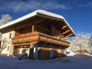 una baita di tronchi con neve sul tetto di Ferienwohnung Lederer a Fieberbrunn