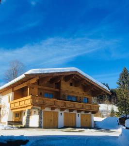 una baita di tronchi con neve sul tetto di Ferienwohnung Lederer a Fieberbrunn