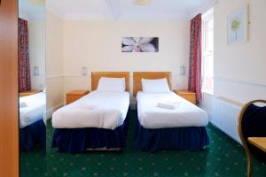 a hotel room with two beds and two nightstands at The Bournemouth Maemar Hotel in Bournemouth