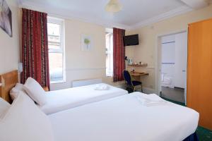 a hotel room with two beds and a desk at The Bournemouth Maemar Hotel in Bournemouth