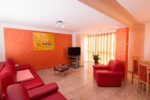 a living room with red chairs and a tv at Pensiunea Haus Paltinul in Sibiu