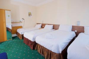 a hotel room with two beds and two tables at The Bournemouth Maemar Hotel in Bournemouth
