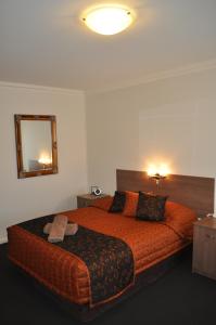 a bedroom with a large orange bed with a mirror at Augusta Courtyard Motel in Port Augusta