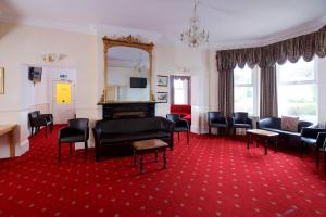 a living room with chairs and a fireplace and a red carpet at The Bournemouth Maemar Hotel in Bournemouth
