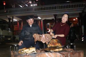 a man and a woman standing next to a table with meat at Moc Chau Town - Homestay in Mộc Châu