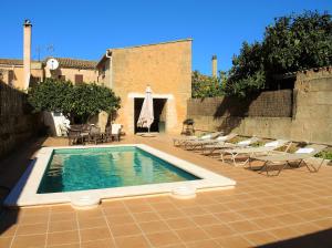 een zwembad op een binnenplaats met stoelen en een gebouw bij Casa Campet in Algaida