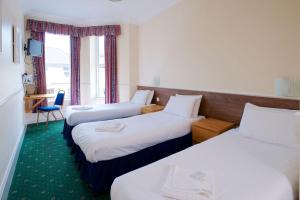a hotel room with two beds and two windows at The Bournemouth Maemar Hotel in Bournemouth