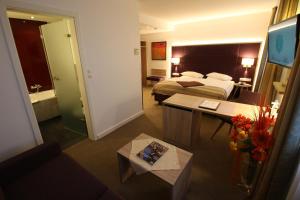ein Hotelzimmer mit einem Bett und einem Wohnzimmer in der Unterkunft Hotel zum Adler - Superior in Bonn
