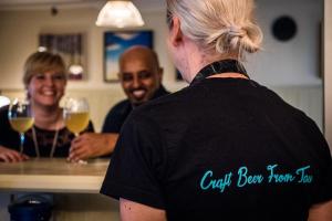two people standing at a counter with wine glasses at Lilland Brewery Hotel in Tau