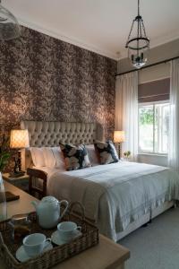 1 dormitorio con 1 cama grande y papel pintado con motivos florales en Cape Vue Country House, en Franschhoek