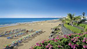 a beach with chairs and umbrellas and the ocean at Rooms & Suites The Lighthouse in Tías