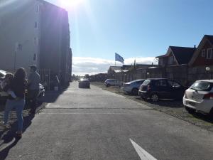 dos personas caminando por una calle con coches aparcados en Departamento Volcán Corcovado, en Puerto Montt