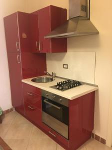 uma cozinha com armários vermelhos, um fogão e um lavatório em La Casetta Due em Teramo