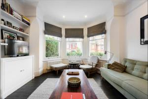 ein Wohnzimmer mit einem Sofa und einem Tisch in der Unterkunft Gorgeous, 4 Bed Victorian house in Dollis Hill in London