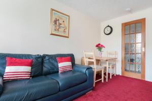 a living room with a blue leather couch and a table at Polwarth Apartment in Edinburgh