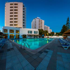 a large swimming pool with chairs and buildings at Janelas do Mar Apartamentos Turisticos in Albufeira +80 photos