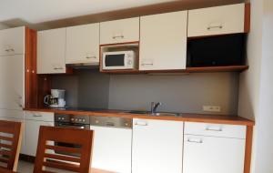 uma cozinha com armários brancos e um micro-ondas em Ferienhaus Hubertus - PRECHTLHOF em Flachau
