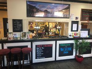 a restaurant with a bar with stools and a tv at The Globe Inn in Gosforth