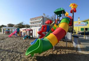un parque infantil con un tobogán en la arena en Hotel Rex, en Senigallia
