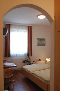 a bedroom with a bed and a desk and a window at Weingut-Pension Stockingerhof in Dürnstein
