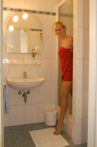 une femme en robe rouge debout dans une salle de bains dans l'établissement Weingut-Pension Stockingerhof, à Dürnstein