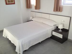 a bedroom with a large white bed with a night stand at Pension La Puntica in Lo Pagán