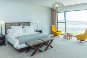 a bedroom with a bed and chairs and a large window at Schulphoek House in Hermanus