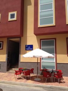a table and chairs and an umbrella in front of a building at Pension La Puntica in Lo Pagán
