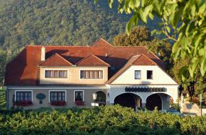 a large white house with a red roof at Weingut-Pension Stockingerhof in Dürnstein