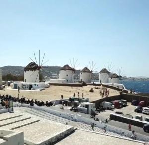 a group of people on a beach with windmills at Christy Suites by Alpha Living in Mýkonos City