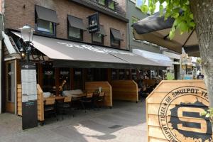 um restaurante com mesas e cadeiras em frente a um edifício em Boutique Hotel De Smulpot em Den Burg