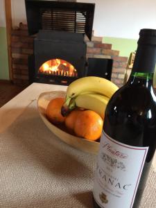 a bottle of wine next to a bowl of fruit and a bowl of bananas at Chalet Breza in Kolašin