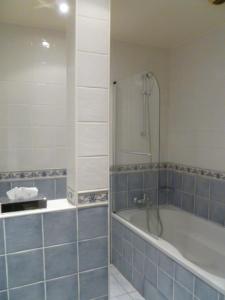 a bathroom with a tub and a shower with blue tiles at Au limousin in Levallois-Perret