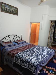 um quarto com uma cama com um cobertor azul e branco em Sobitai em Palolem