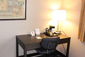 a desk in a hotel room with a lamp and a chair at Days Inn by Wyndham Watertown in Watertown