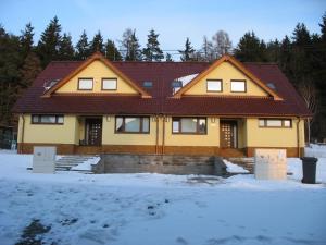 a yellow house with a brown roof in the snow at Dvojdům Ostrov u Macochy in Ostrov u Macochy