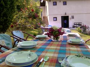 a table with plates and utensils and flowers on it at Vikend kuća Careva Ćuprija-apartman in Olovo