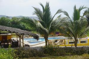 a pool with palm trees in front of a resort at Hosteria Tsafiki in Puerto López