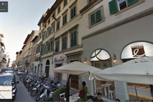 a street with tables and umbrellas in front of buildings at Love weekend near Piazza Ognissanti in Florence