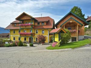 ein großes gelbes Haus mit braunem Dach in der Unterkunft Landhaus Ebner in Millstatt