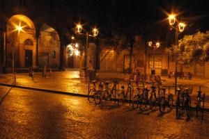 um grupo de bicicletas estacionadas numa rua à noite em La Maison della piazzetta em Bolonha