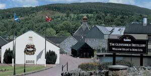 a building with a sign in front of a mountain at Acorn Apartment in Dufftown