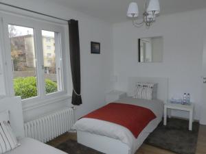 a white bedroom with a bed and a window at Au Bonheur des Iris in Rolle